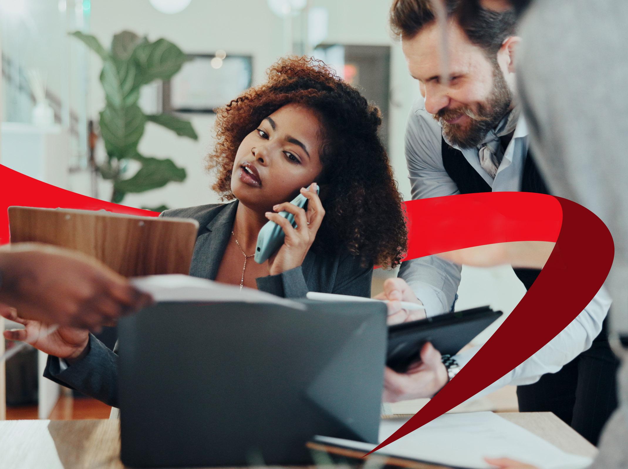 A woman on the phone, stressed and surrounded by demanding coworkers, illustrating the need for better priority management.