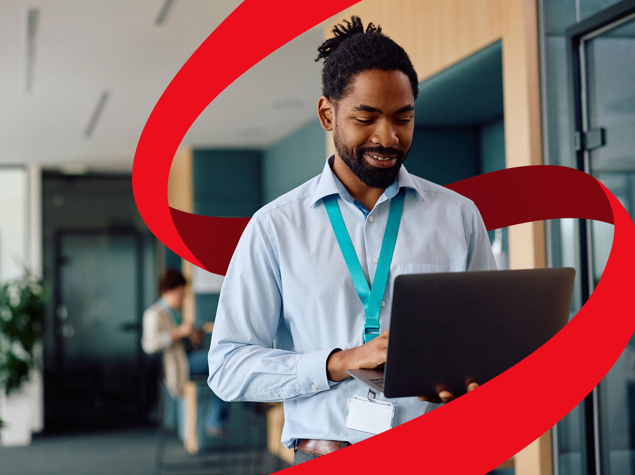 IT professional working on a laptop while standing in an office setting.