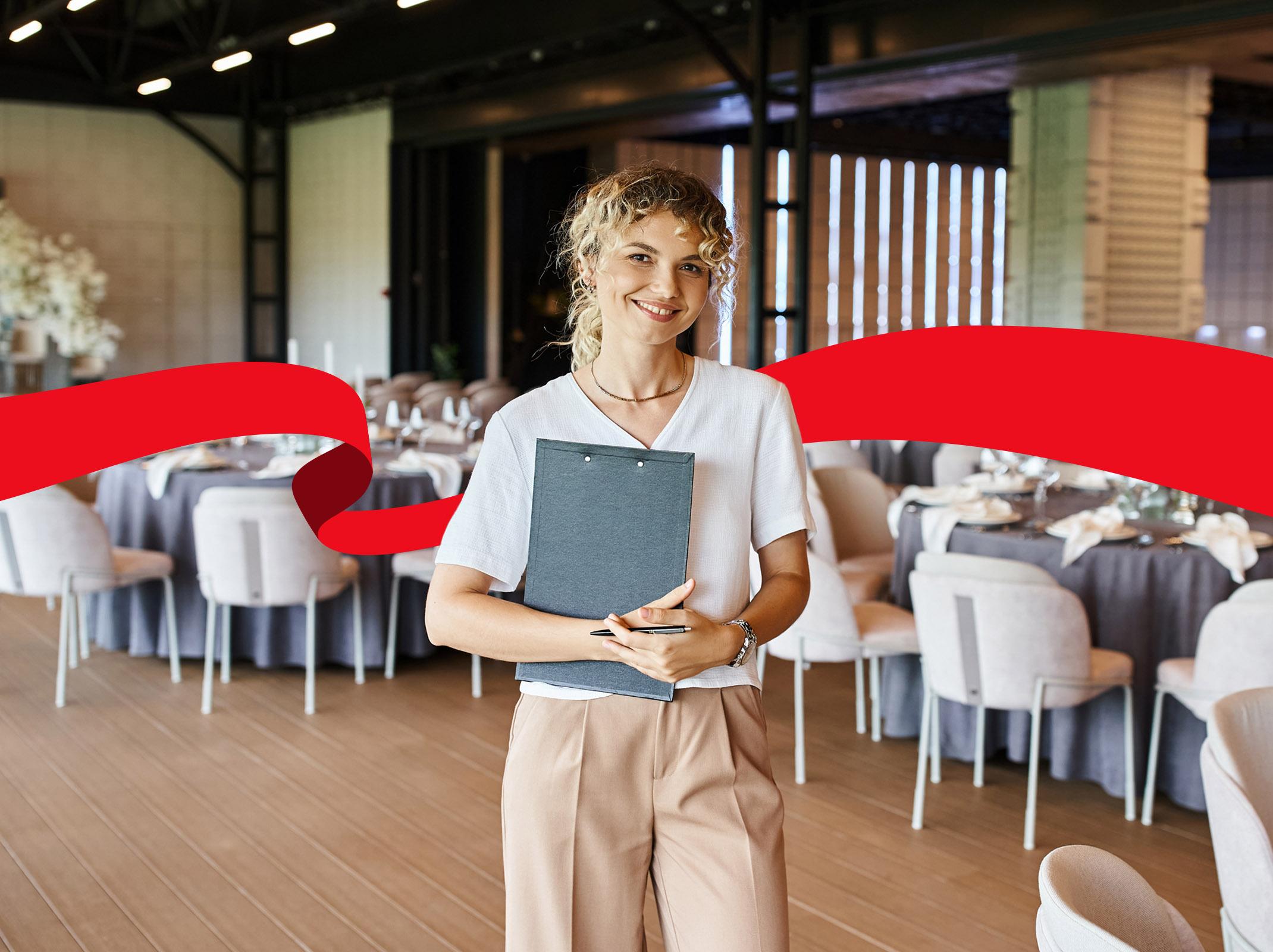 Smiling event planner standing in front of decorated event tables with candles and place settings