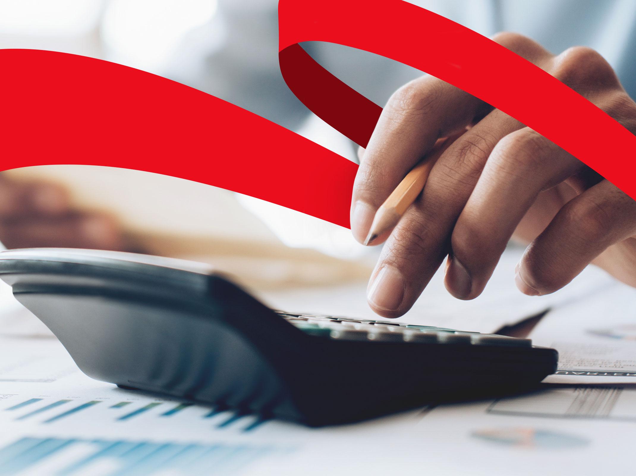 Business professional reviewing a budget with paper, pencil and a calculator in an office setting.