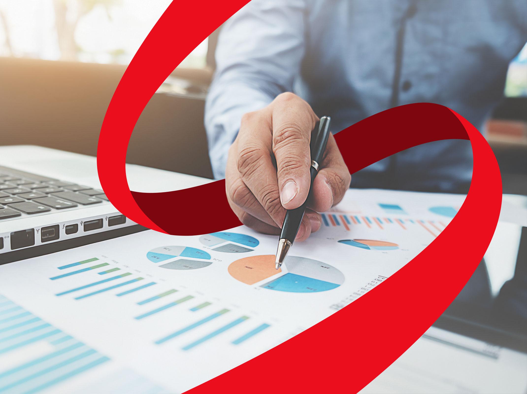 Business professional pointing at analytical charts and graphs) in front of a laptop in a business setting.