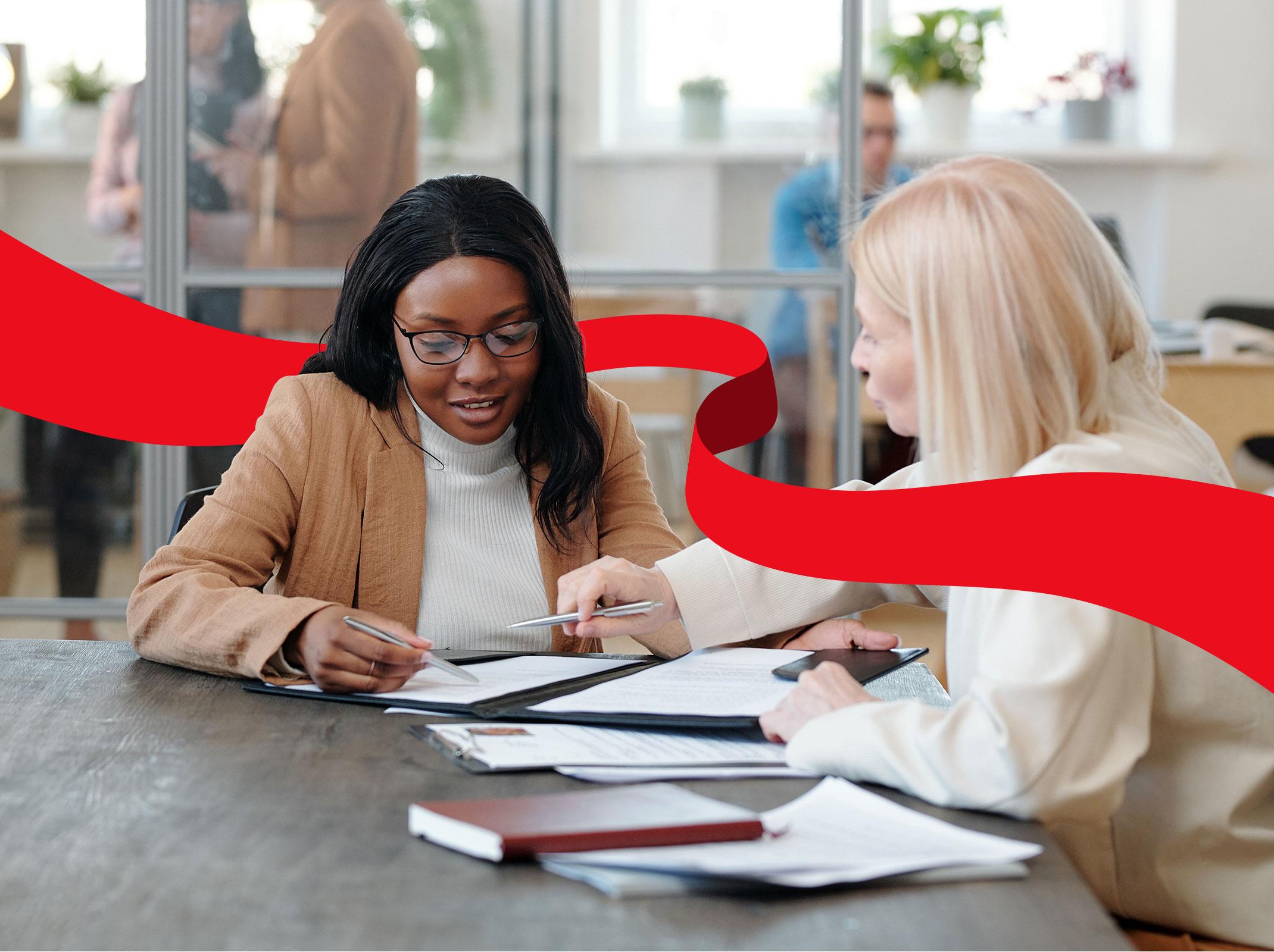 Two human resources professionals reviewing documents at a conference table