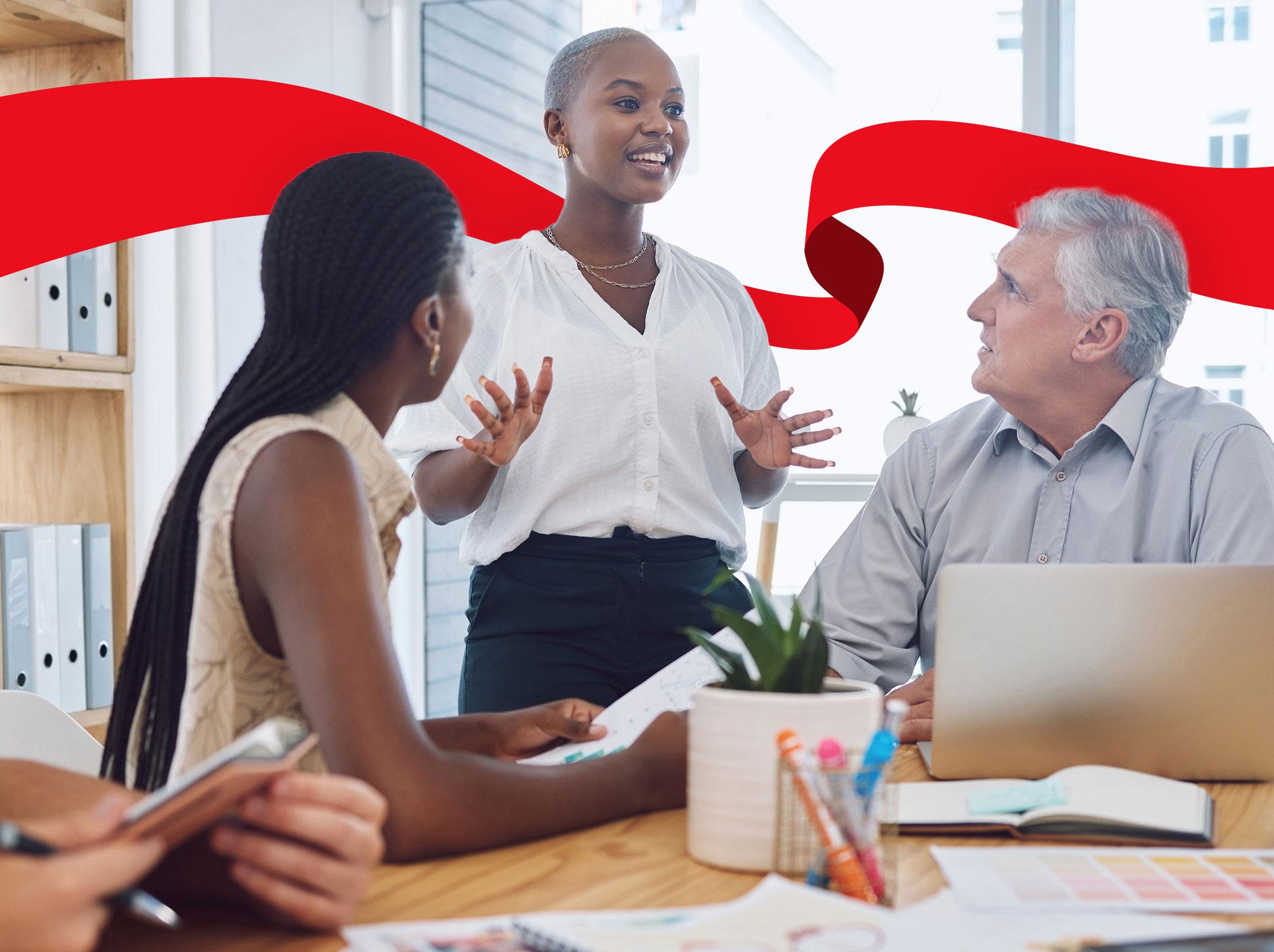 A leader explaining something to a group of three other professionals.  She is standing and gesturing with her hands.