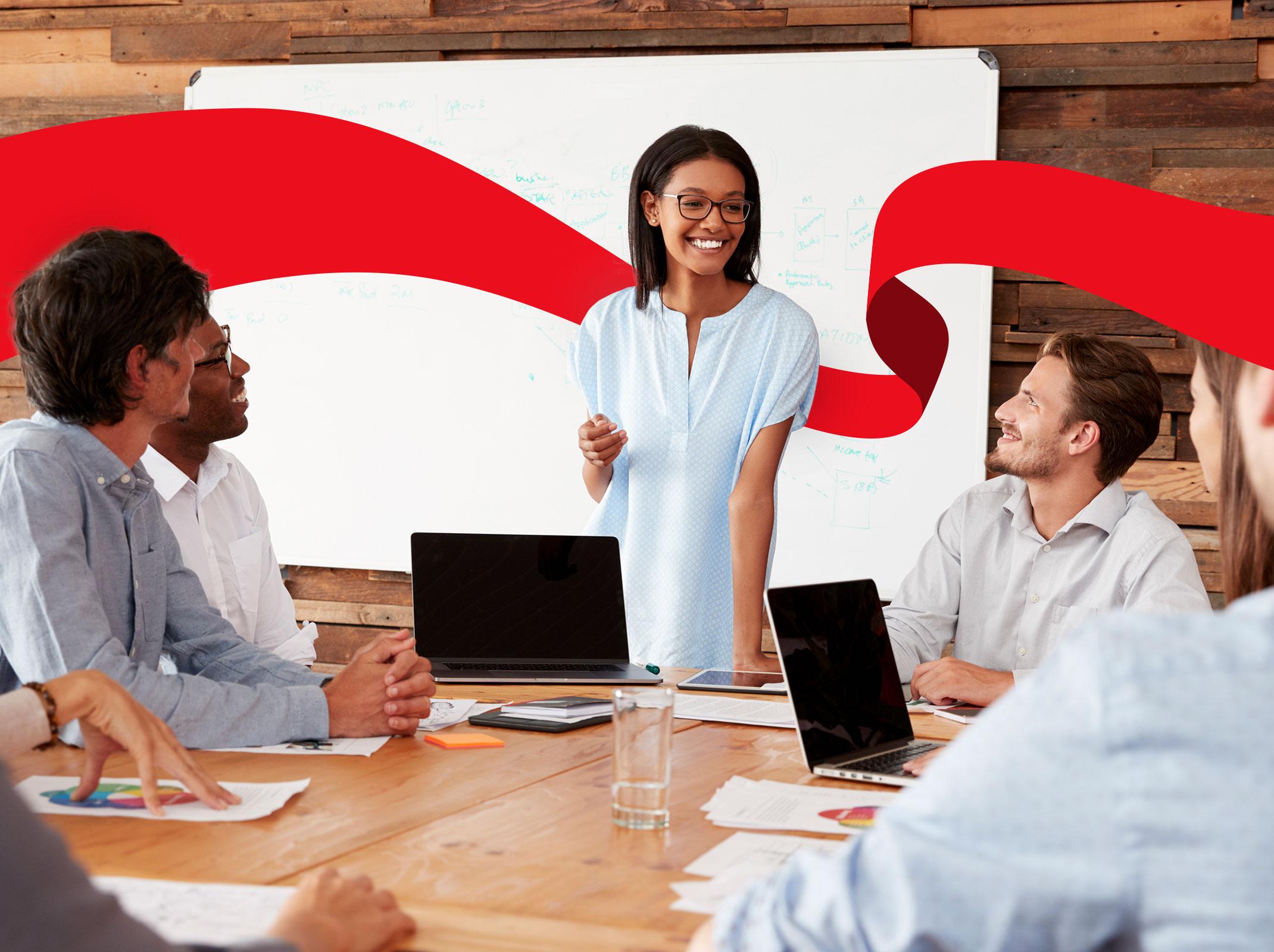 Professional woman leading a team of people around a conference table in a business setting.