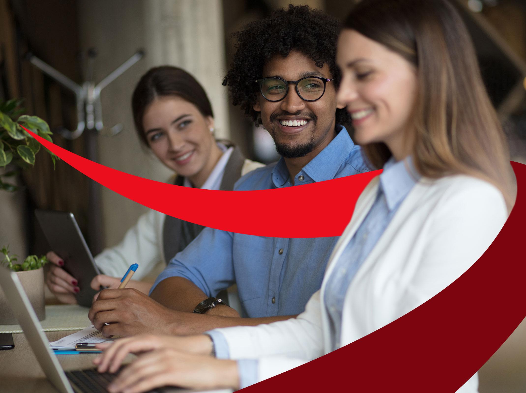 The image shows a diverse group of four new managers in a business meeting around a conference table. They are engaged in discussion, with documents and a laptop present in a modern office setting.
