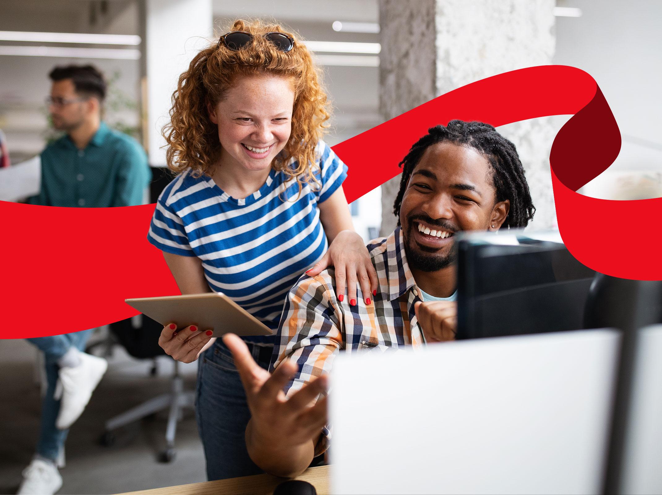 Two business professionals that appear to have a good working relationship laughing as they work together at a laptop.